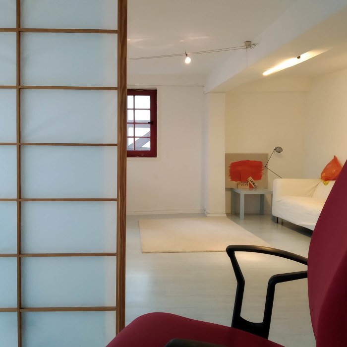 Ein Bürostuhl, ein Sofa, ein orangenes Bild im Hintergrund, davor ist ein zerschlagenes Brett